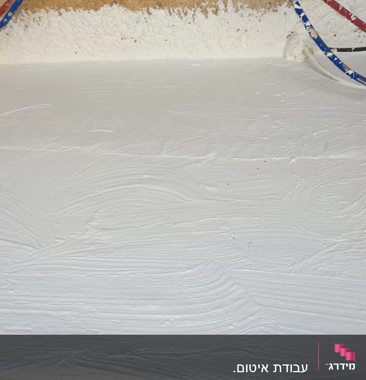 שכבת איטום לבנה על משטח עם צינורות צבעוניים